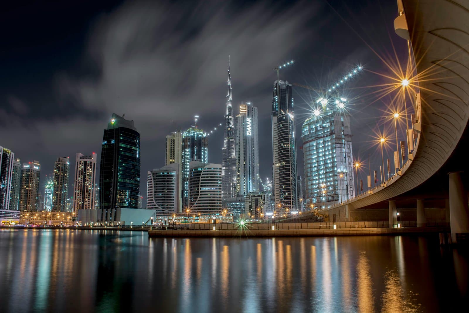 Stunning night view of Dubai's illuminated skyline featuring the iconic Burj Khalifa and waterfront reflections.